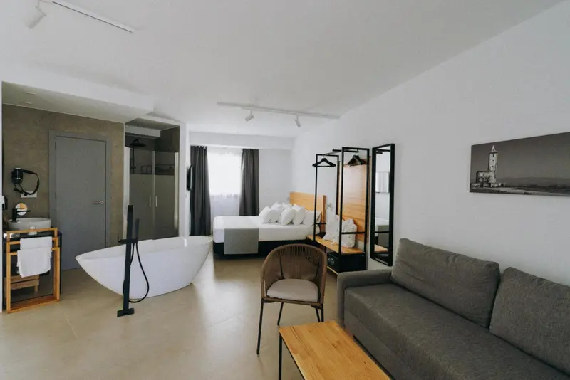 Une chambre lumineuse avec un canapé, un lit et une baignoire sur pieds.