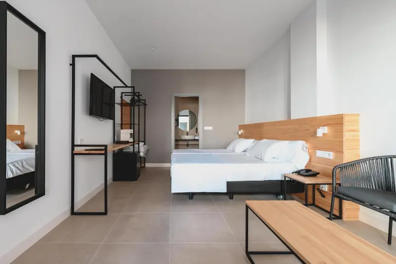 Chambre lumineuse avec un grand lit et un coin salon.