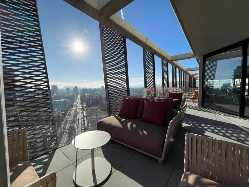 Espace de détente extérieur avec canapés et table basse offrant une vue sur la ville.