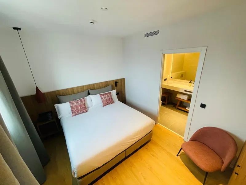Une chambre lumineuse avec un grand lit et un fauteuil.