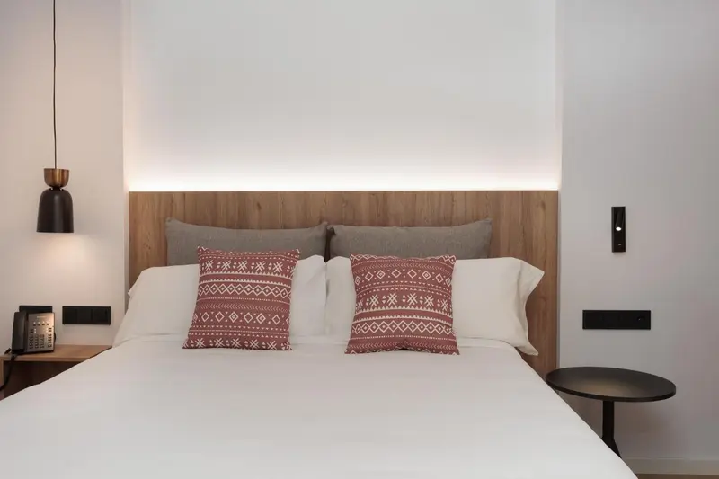 Un lit double avec une décoration soignée dans une chambre lumineuse.