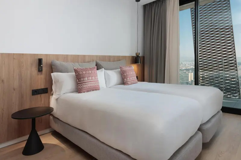 Un lit double avec oreillers et couvertures blanches dans une chambre moderne.