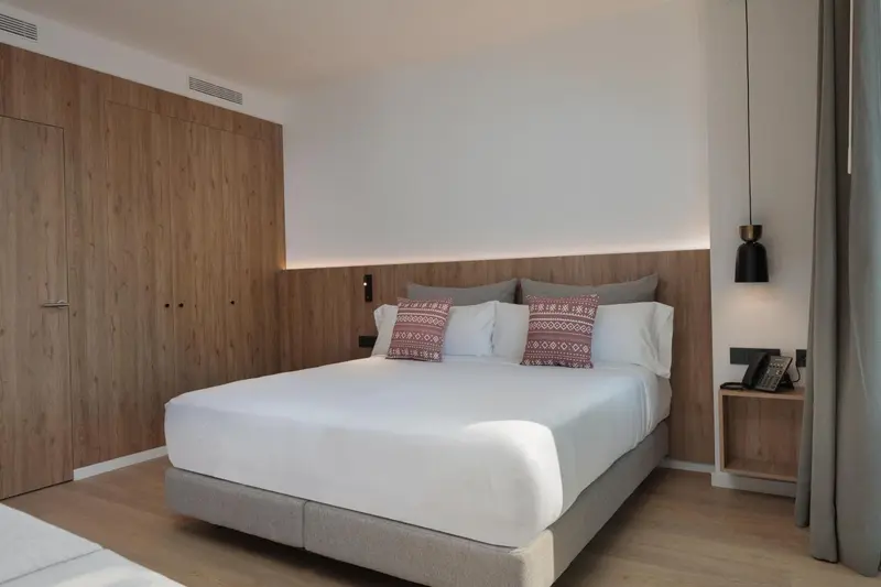 Une chambre lumineuse avec un grand lit recouvert de draps blancs et d'oreillers.