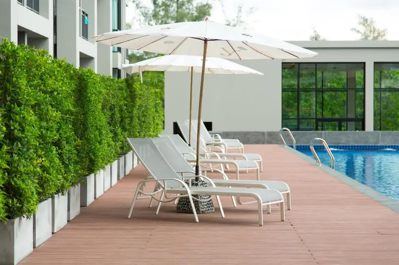 Transats blancs alignés au bord d'une piscine ensoleillée.