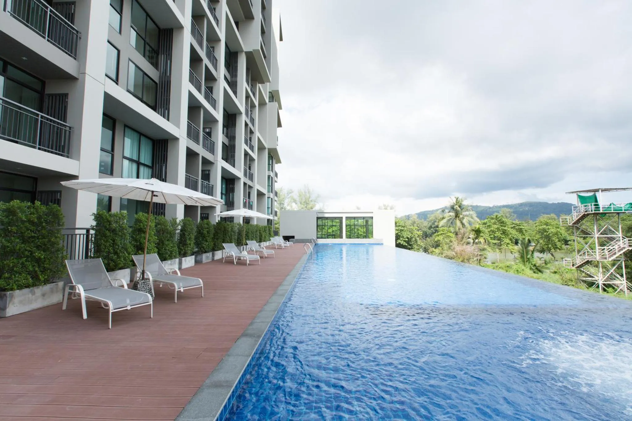 Terrasse avec transats blancs au bord d'une piscine rectangulaire.