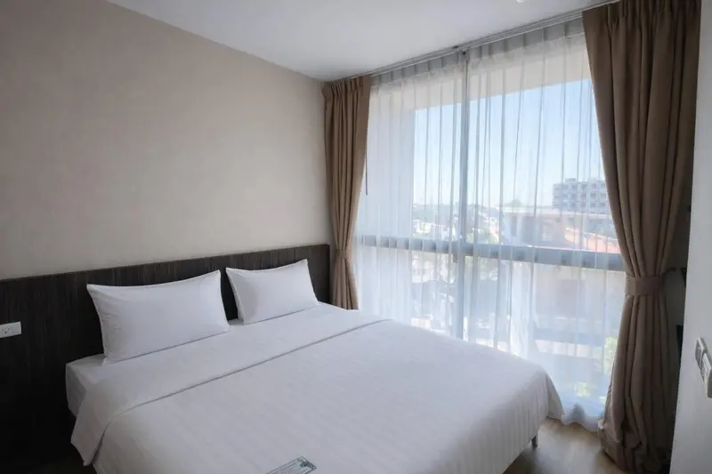 Une chambre lumineuse avec un grand lit et de larges fenêtres.