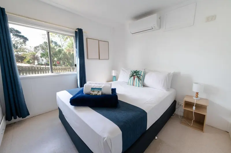 Une chambre lumineuse avec un grand lit recouvert d'une courtepointe.