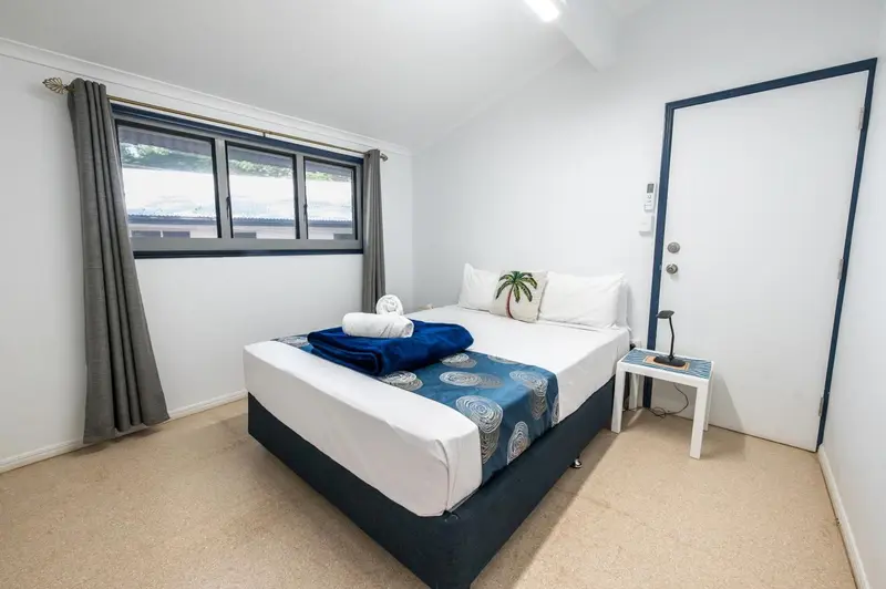 Une chambre lumineuse avec un grand lit recouvert d'une courtepointe bleue et blanche.