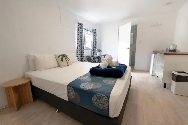 Une chambre lumineuse avec un lit fait et un coin repas.