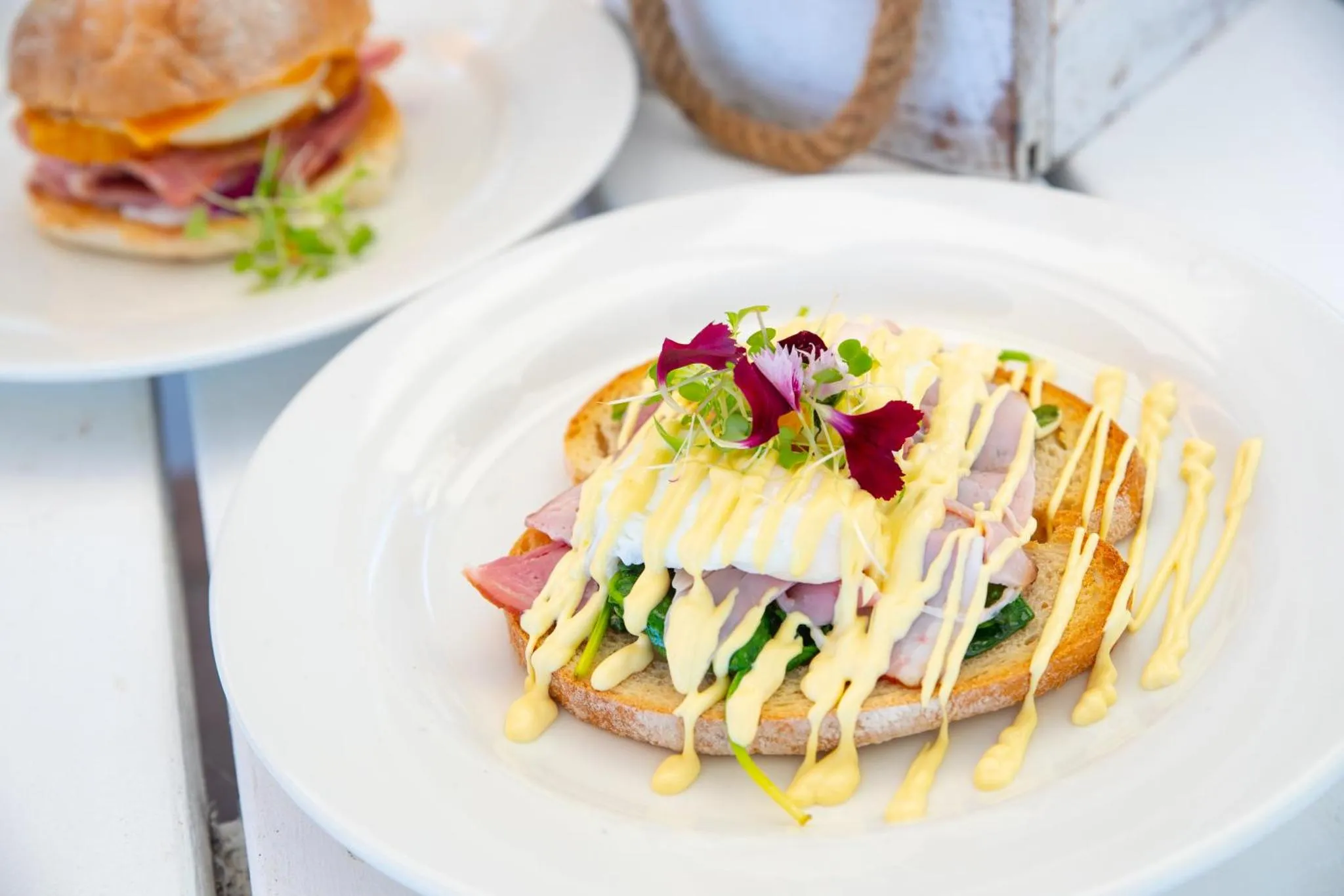 Assiettes de sandwichs garnis servis sur une table blanche.