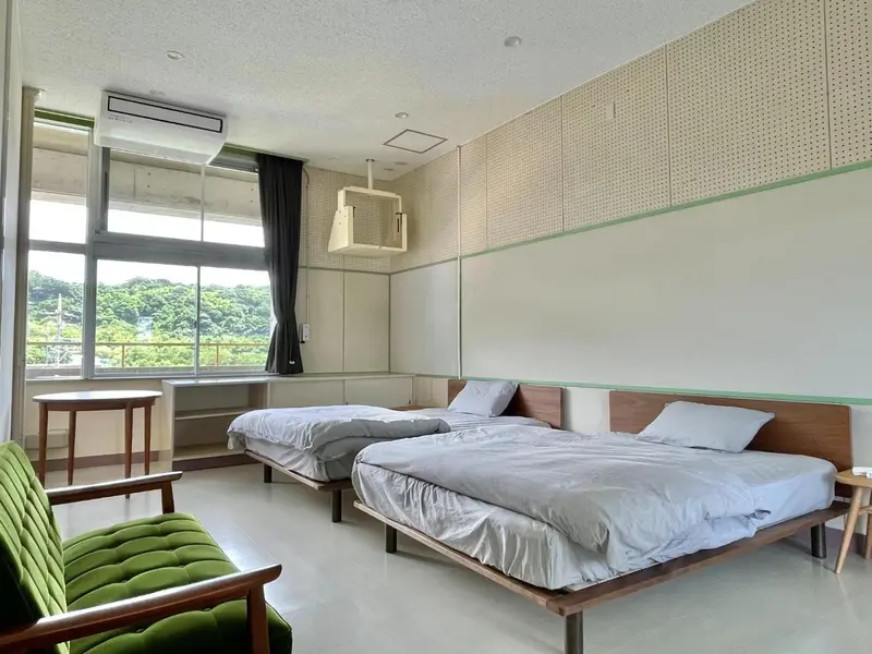 Une chambre lumineuse avec deux lits simples et une vue sur la végétation.