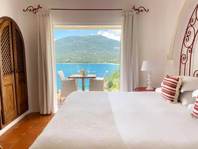 Une chambre lumineuse s'ouvre sur une vue imprenable sur la mer et les montagnes.