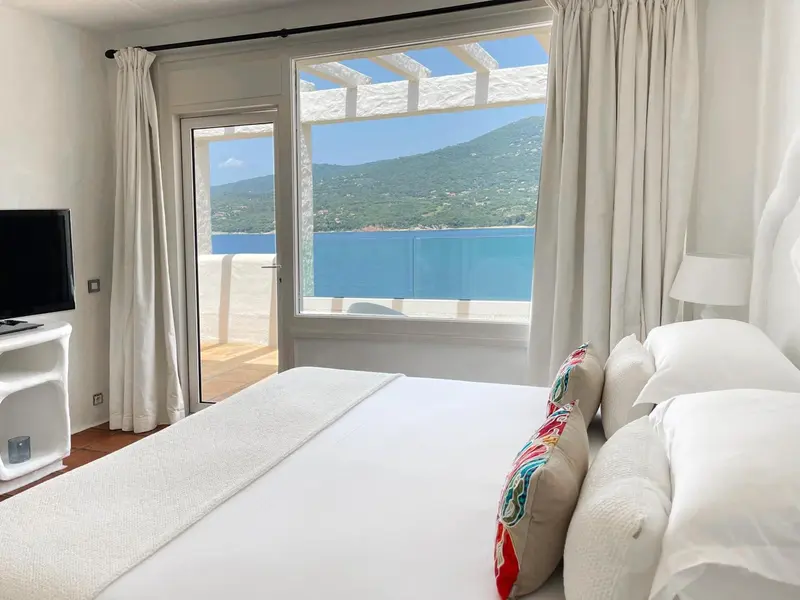 Une chambre lumineuse avec un lit fait et une vue sur la mer.