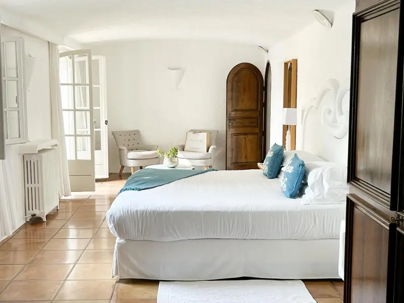 Une chambre lumineuse avec un grand lit recouvert d'une couverture bleue et de coussins.