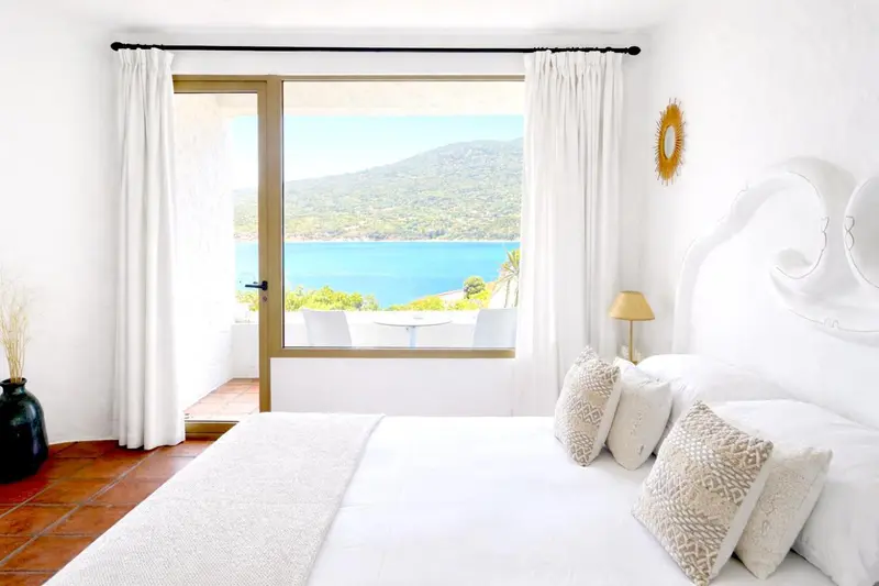 Une chambre lumineuse avec un lit et une vue sur la mer.