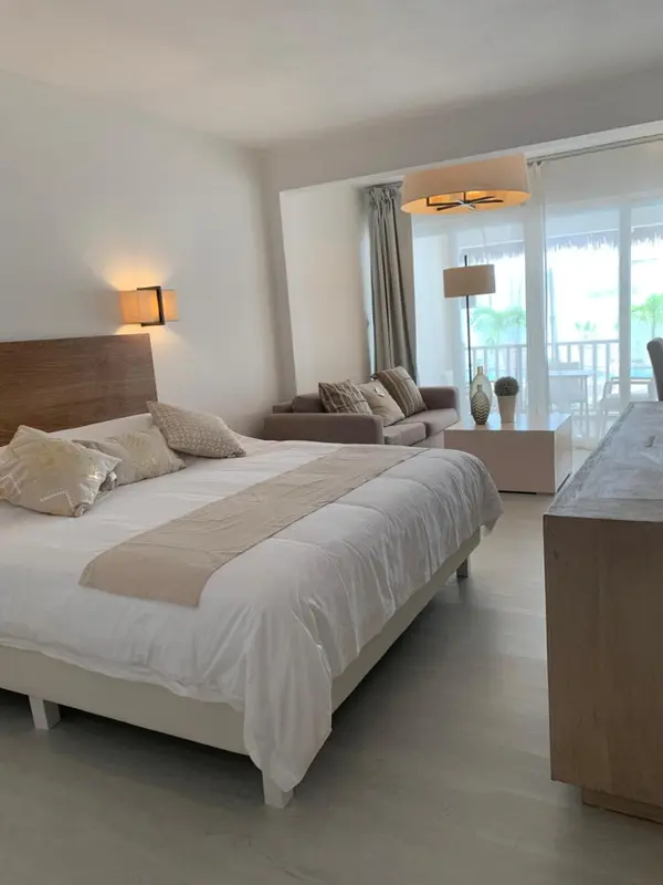 Une chambre lumineuse avec un grand lit et un coin salon.