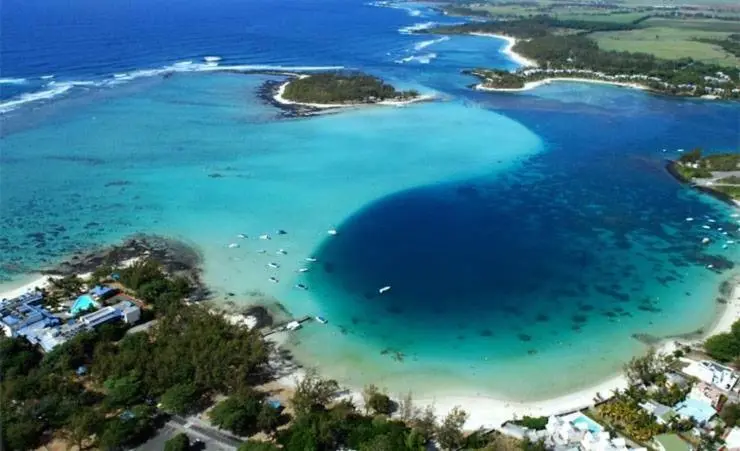 Vue aérienne d'une côte turquoise bordée de plages et de végétation luxuriante.