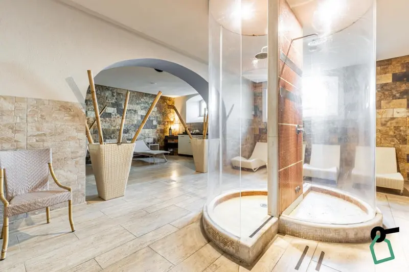 Une salle de bain avec une douche circulaire en verre et un décor en pierre.