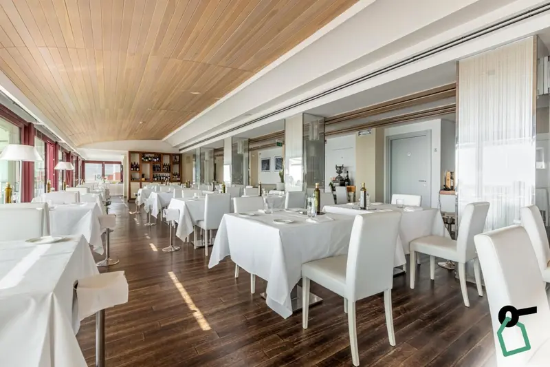 Une salle lumineuse avec des tables dressées pour un service en restaurant.