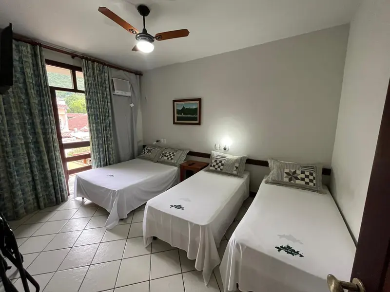 Chambre lumineuse avec deux lits simples et une vue sur la végétation.