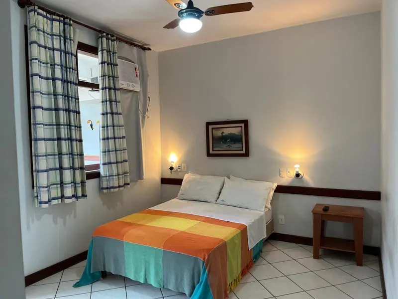Une chambre lumineuse avec un lit recouvert d'une courtepointe colorée et une table de chevet.