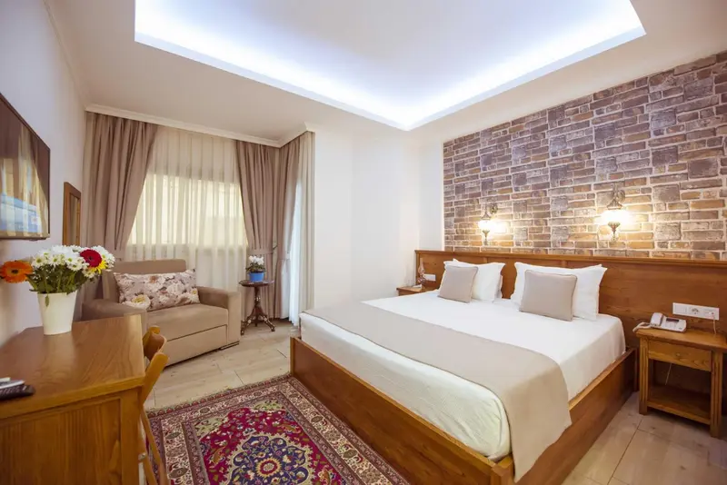 Une chambre lumineuse avec un lit double et un coin salon.