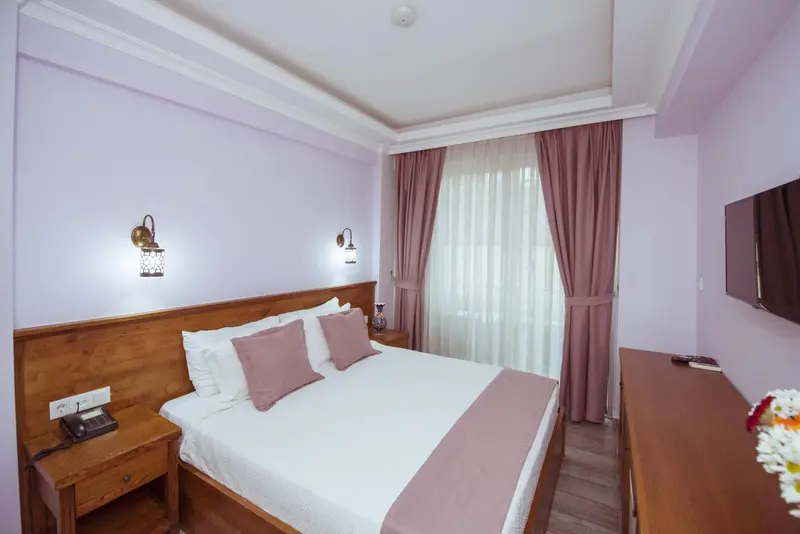 Une chambre lumineuse avec un grand lit recouvert d'une courtepointe rose et de coussins.