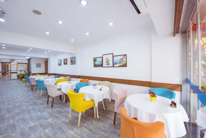 Une salle lumineuse avec des tables et des chaises colorées est prête pour le service.