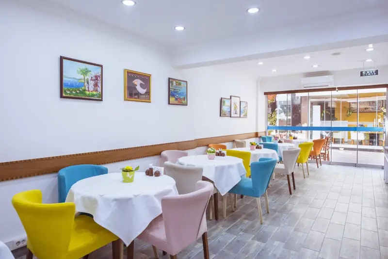 Une salle lumineuse avec des tables colorées et des tableaux décoratifs.