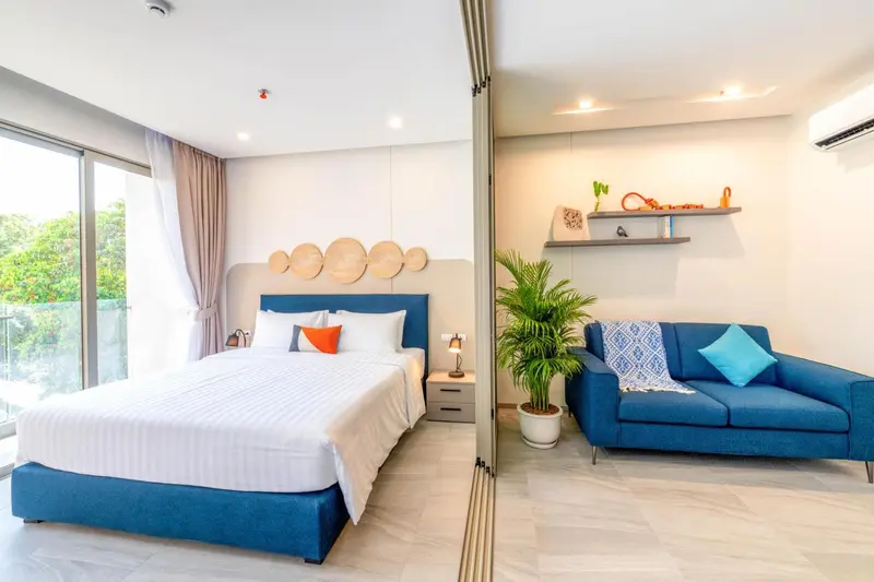 Une chambre lumineuse avec un grand lit et un coin salon bleu.