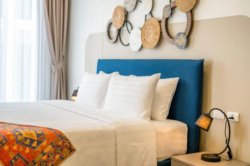 Un lit avec une tête de lit bleue et des oreillers blancs dans une chambre décorée.