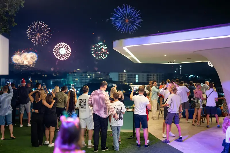 Des spectateurs observent un feu d'artifice depuis une terrasse.