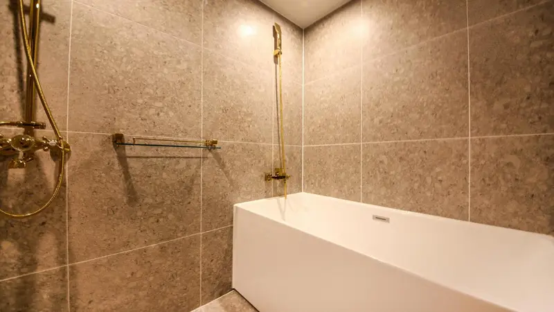 Une douche à l'italienne avec un carrelage beige et des accessoires dorés.