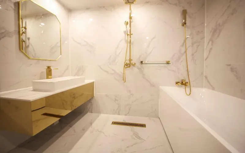 Une salle de bain moderne avec des carreaux de marbre et des accessoires dorés.