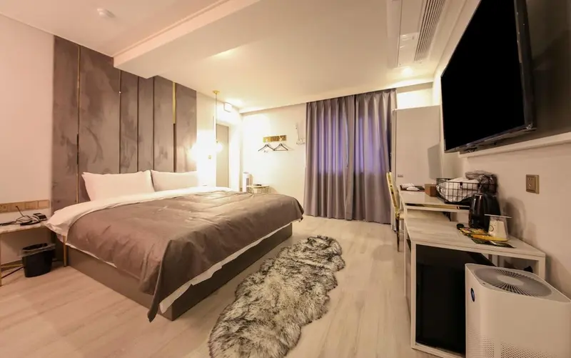 Une chambre lumineuse avec un grand lit et une télévision murale.