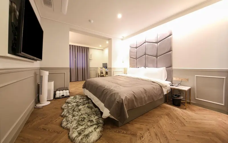Une chambre moderne avec un grand lit et une télévision murale.