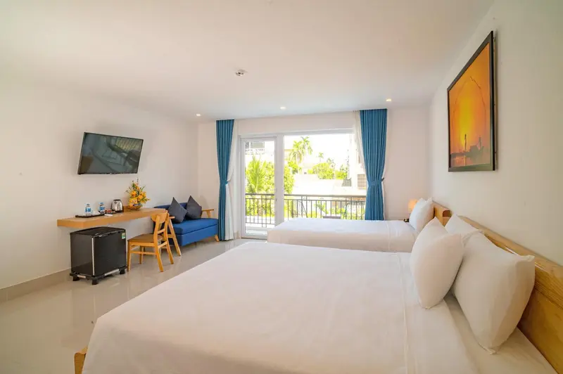 Une chambre lumineuse avec un lit double et un canapé face à une baie vitrée.