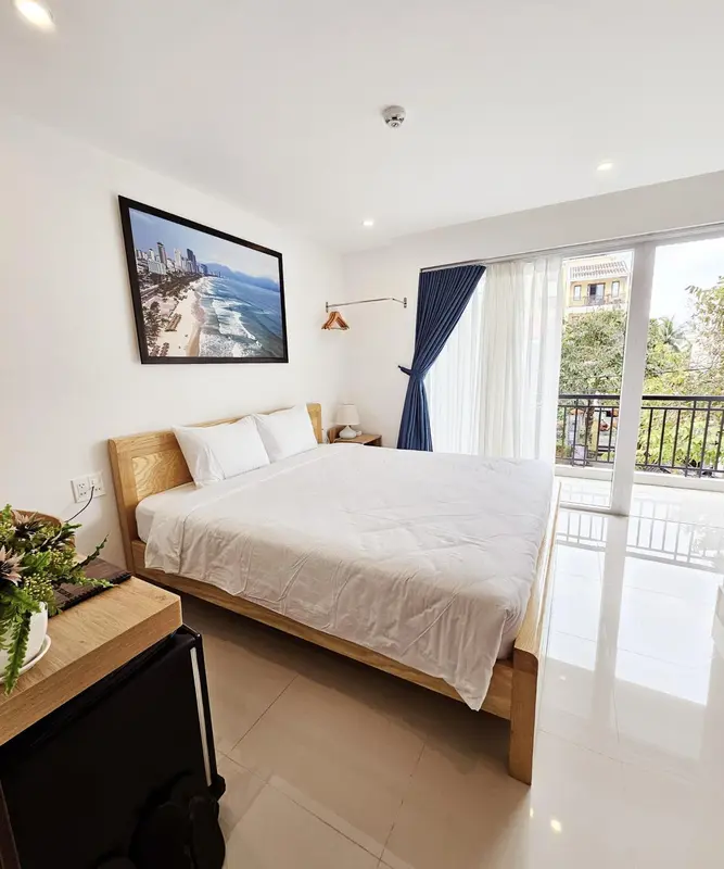 Chambre lumineuse avec un grand lit et une vue sur l'extérieur.