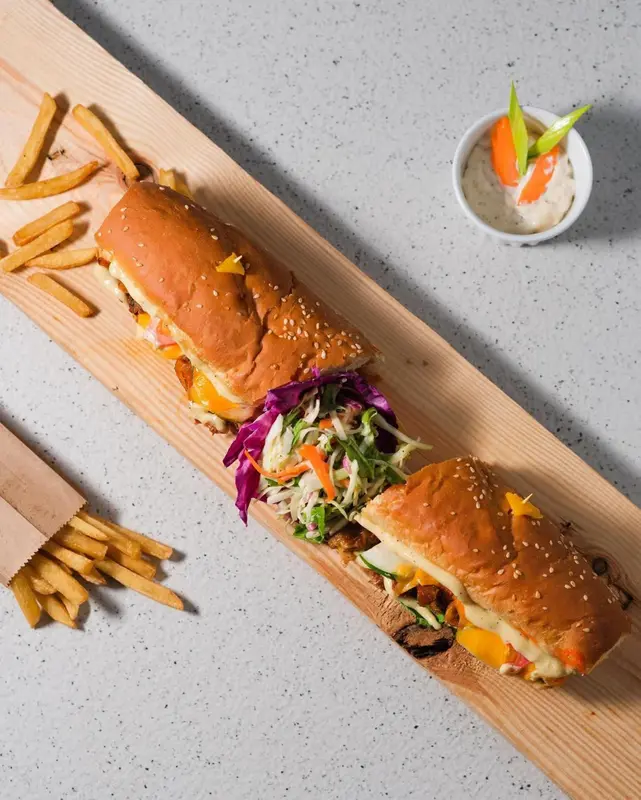 Présentation de sandwichs garnis accompagnés de frites et de crudités.