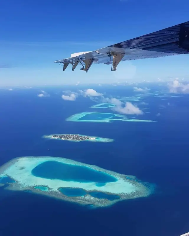 Vue aérienne d'îles tropicales et de récifs coralliens dans une mer turquoise.