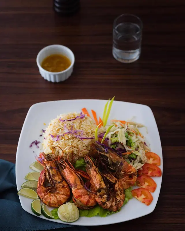 Assiette de riz aux crevettes et salade colorée.