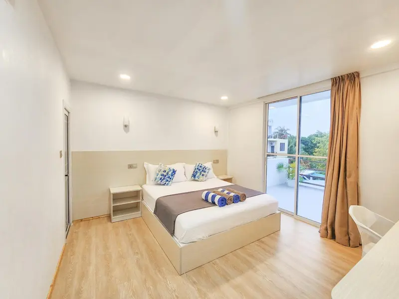 Une chambre lumineuse avec un grand lit et un accès à une terrasse.