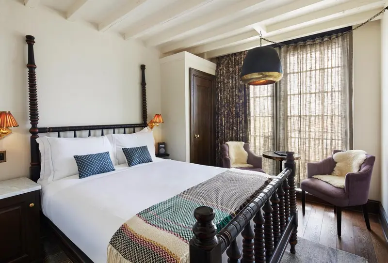Une chambre lumineuse avec un grand lit et deux fauteuils.