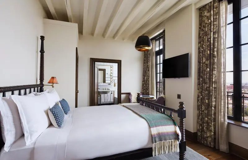 Une chambre lumineuse avec un grand lit et un accès à une fenêtre.
