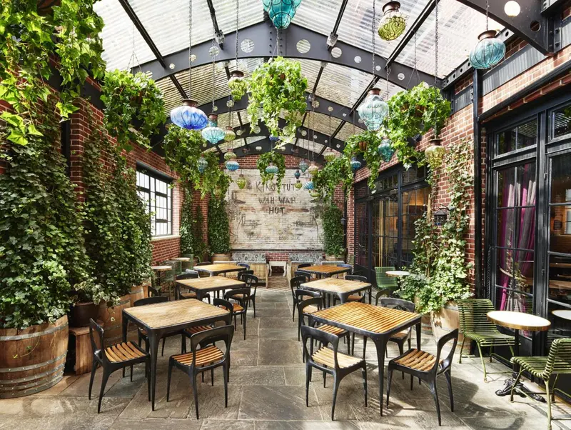 Une cour intérieure végétalisée avec des tables et des chaises.