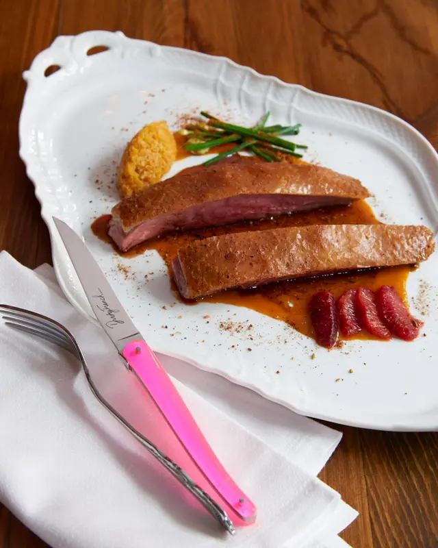 Assiette de viande accompagnée d'une sauce et de légumes.