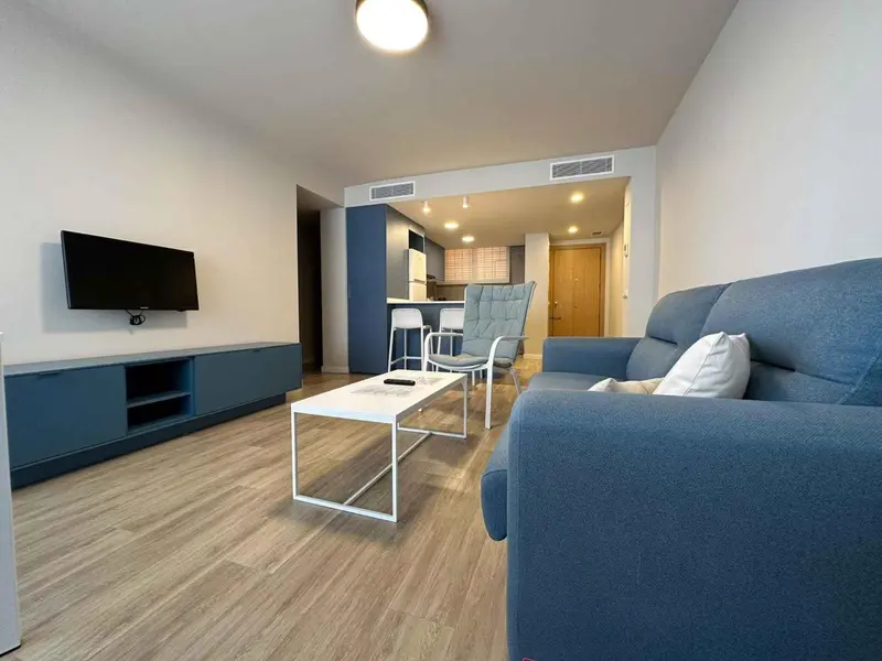 Un salon moderne avec canapé bleu et meuble bas pour télévision.