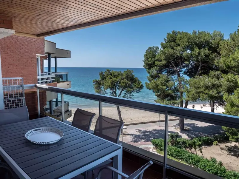 Une terrasse avec une table et des chaises offre une vue sur la mer et la plage.