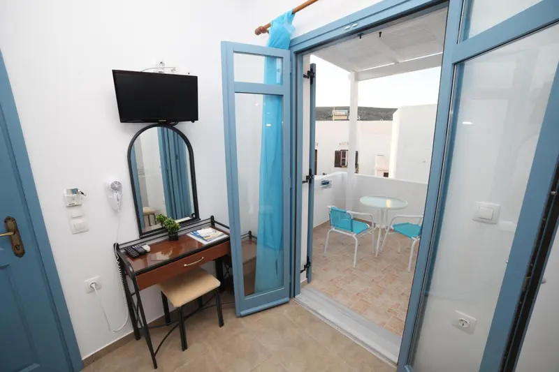 Une chambre lumineuse s'ouvre sur une terrasse avec table et chaises.