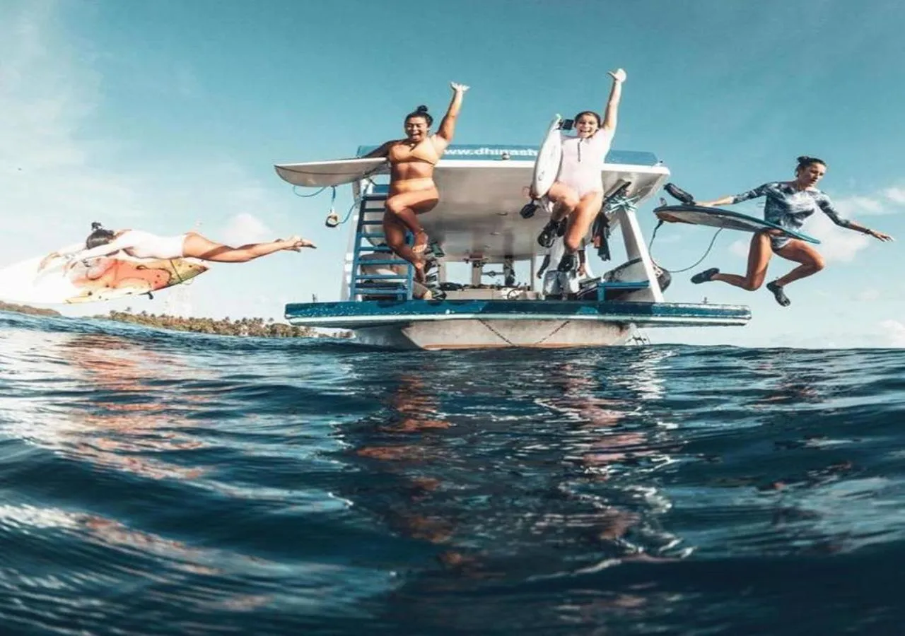 Des personnes sautent d'un bateau dans une mer turquoise.